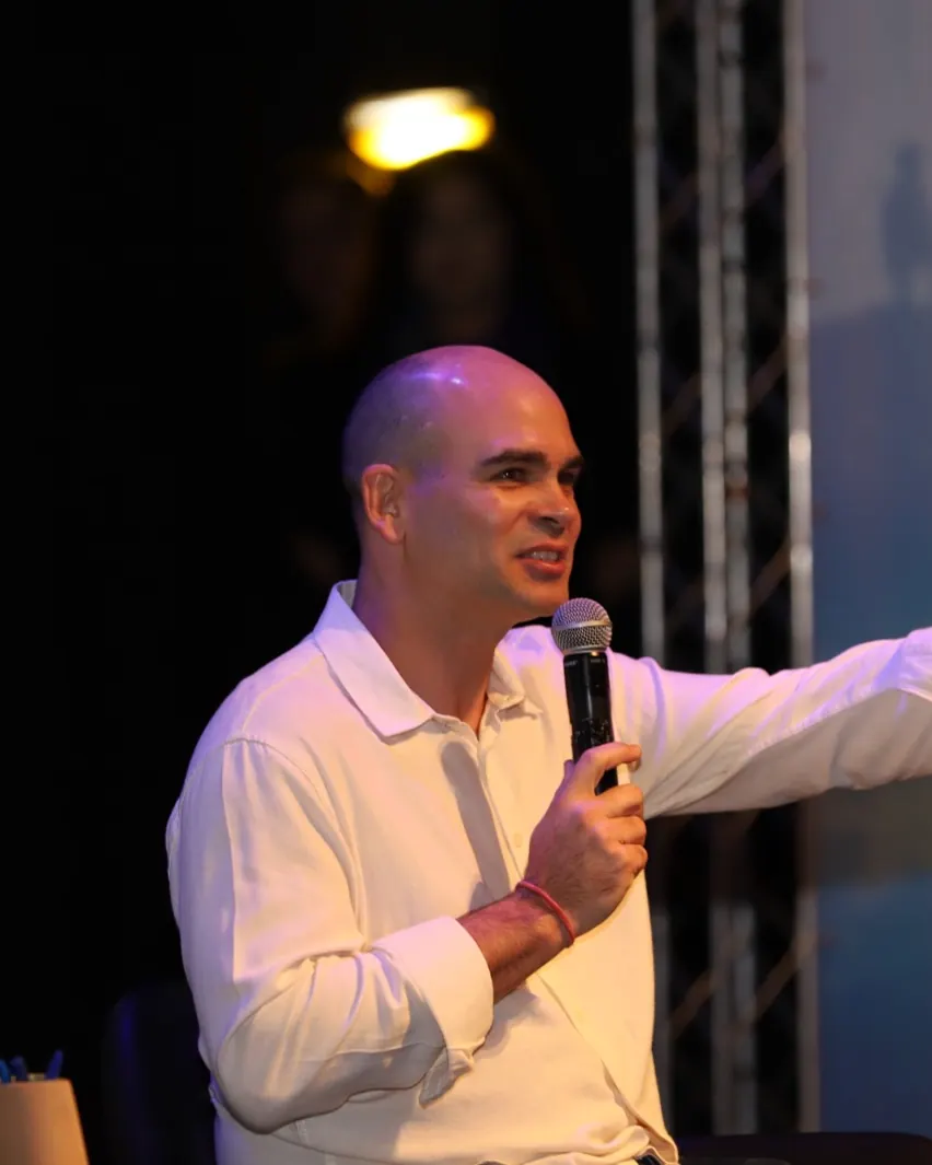 Felipe Lapa no palco, ao microfone, apontando para a plateia
