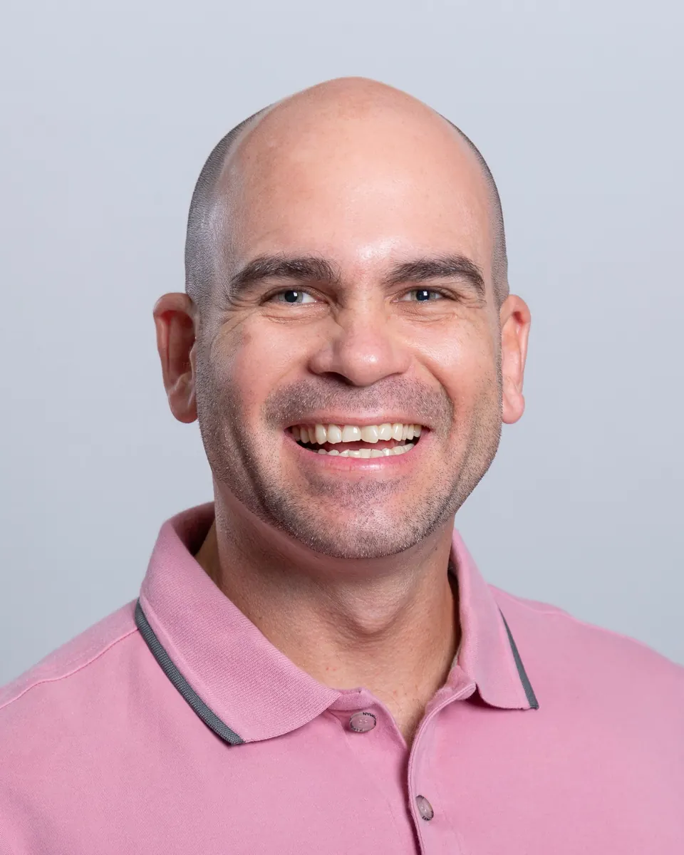 Retrato de Felipe Lapa, de camisa rosa, sorrindo