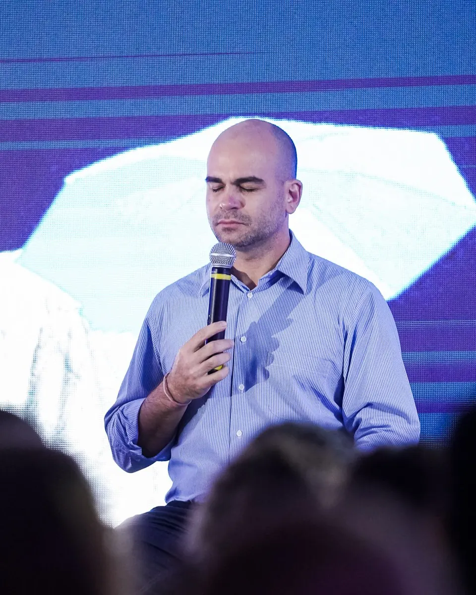Felipe Lapa no palco, de olhos fechados, conduzindo a prática com a plateia