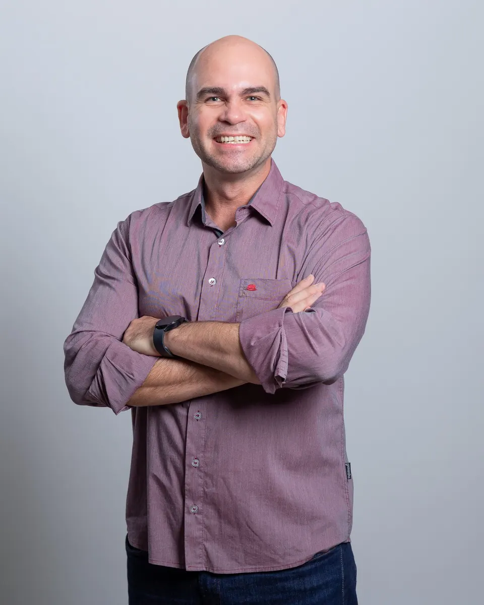 Felipe Lapa de braços cruzados, de camisa vinho, sorrindo