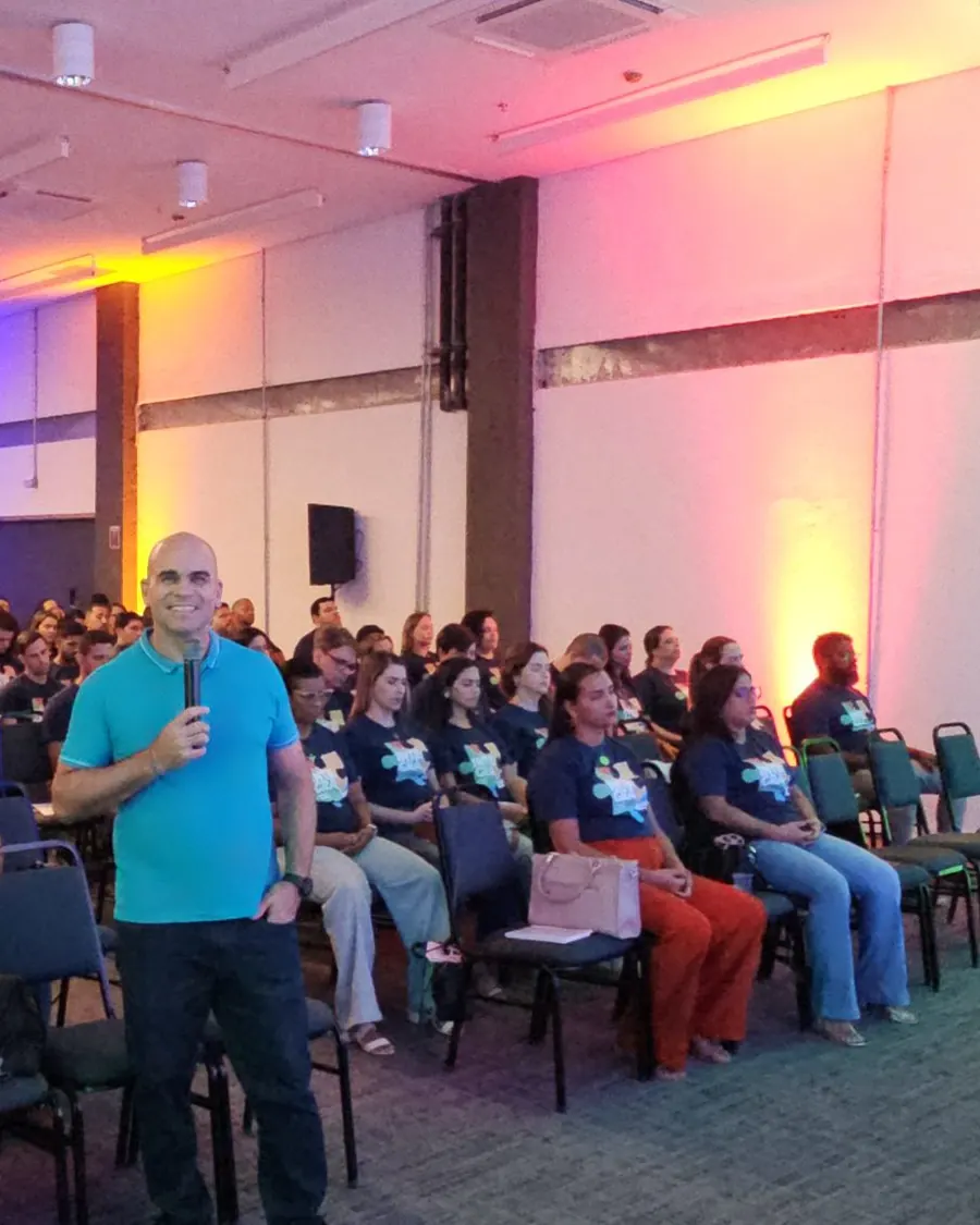 Felipe Lapa ao microfone, no meio de um auditório de educadores